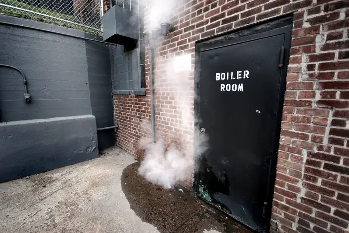 steam leaking from a black door that says the words "boiler room."